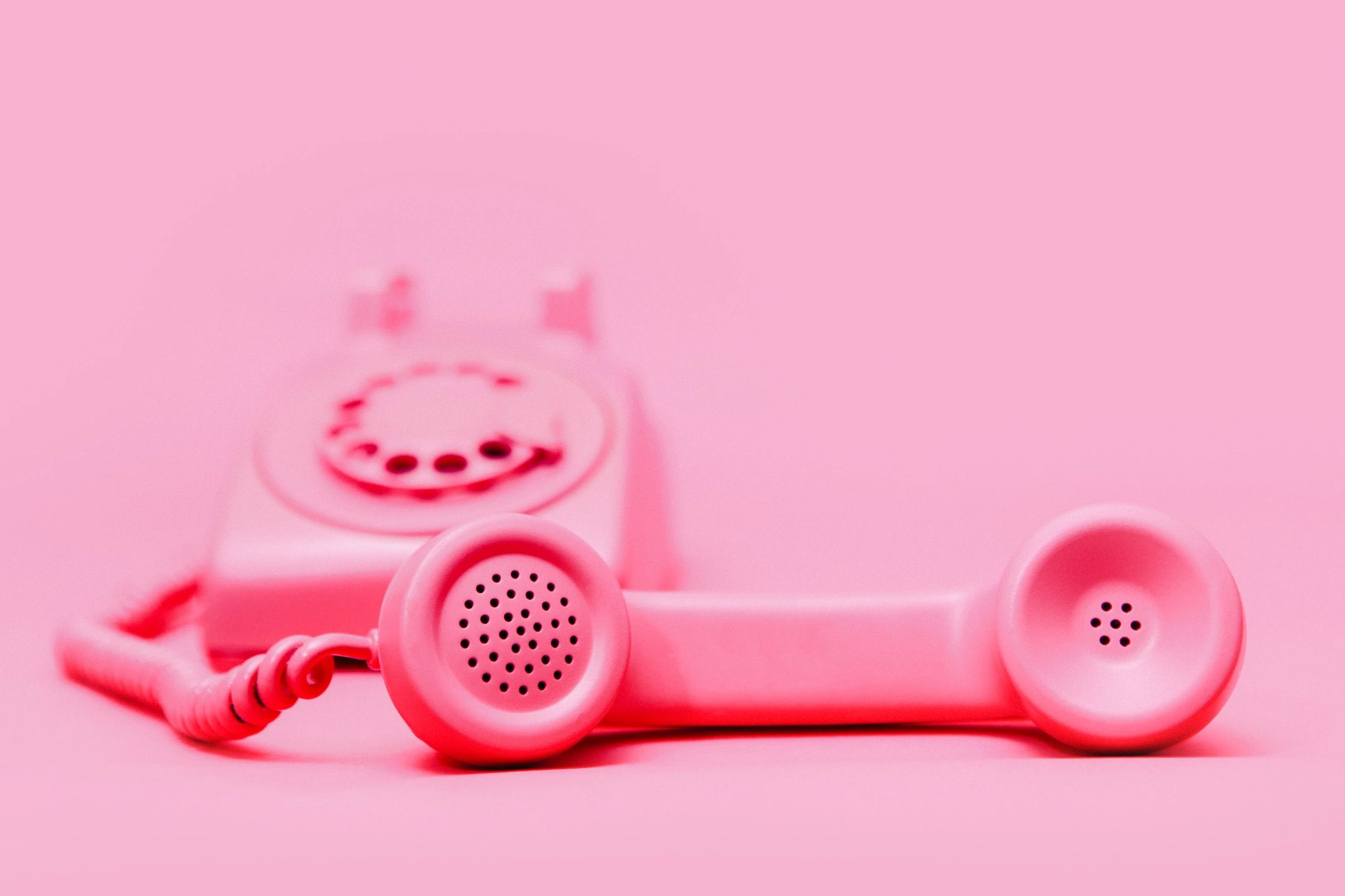 Pink rotary telephone on pink background