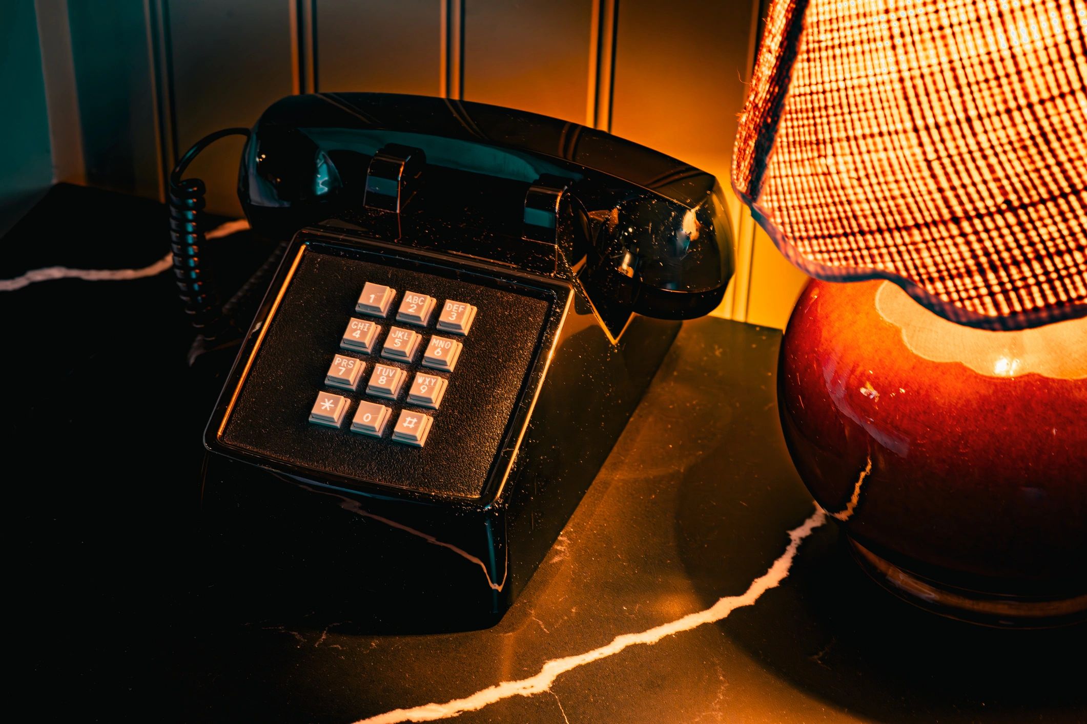 Vintage black rotary phone on a marble surface with lamp